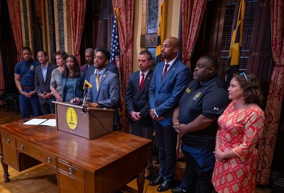 Mayor Scott at podium with people flanking him